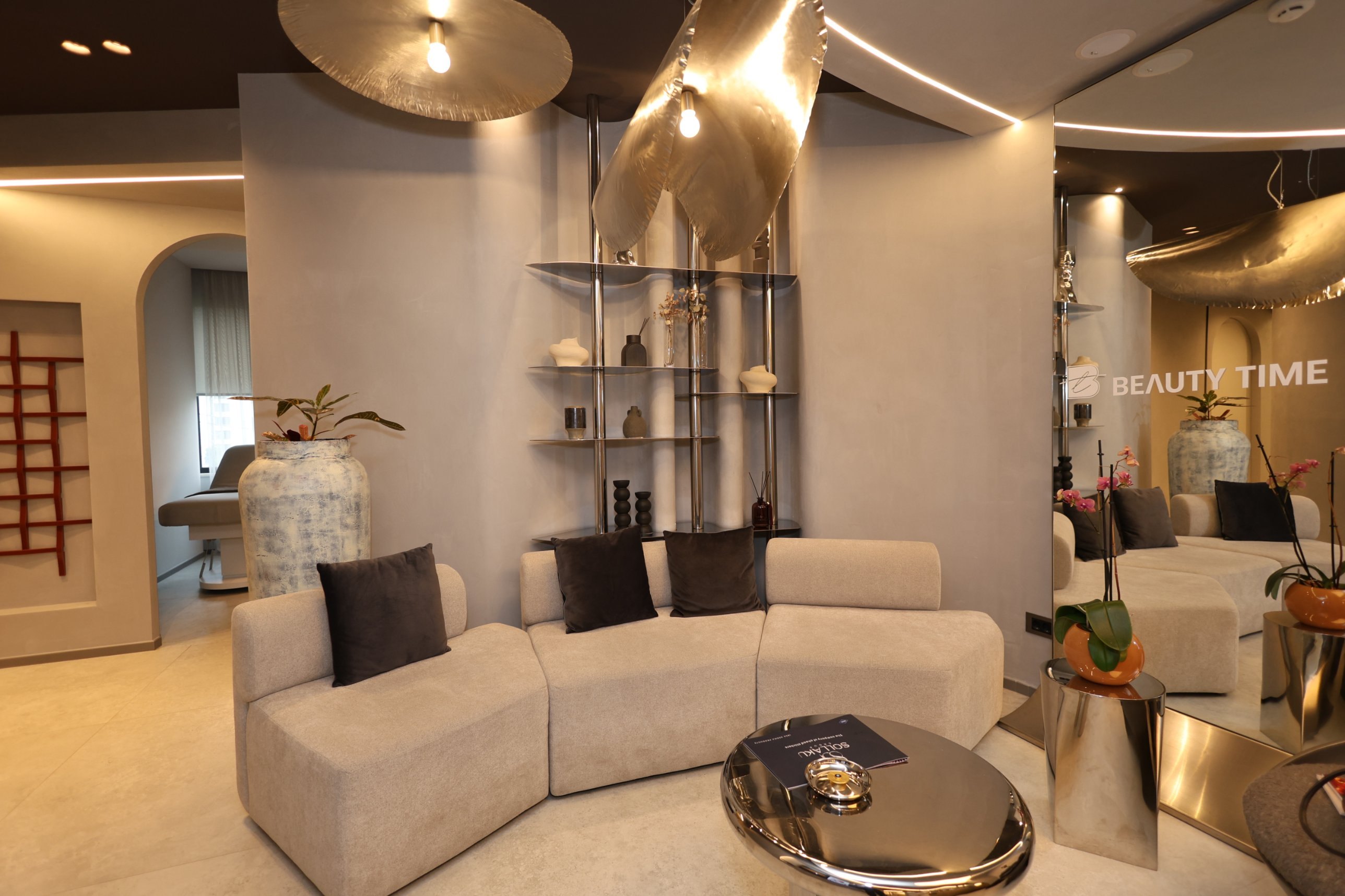 Beauty Time waiting room with a sofa, a mirror-polished stainless steel side table and the steel shelf against a micro-cement wall