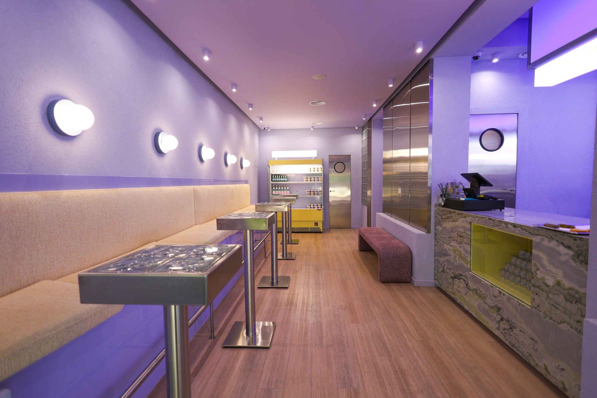 Interior of Bloom the Matcha with brushed stainless steel wall cladding, high tables and tubular steel chairs against lilac walls