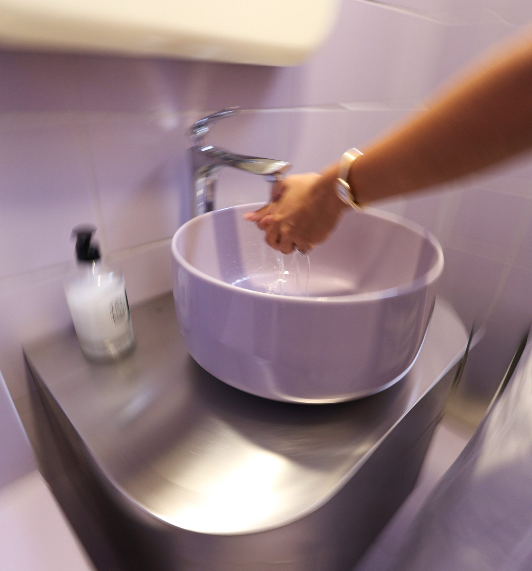 Wall-mounted folded stainless steel vanity with rounded corners in the washroom at Bloom the Matcha