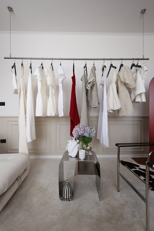 Brushed stainless steel suspended garment rail against the studio wall at Door 903