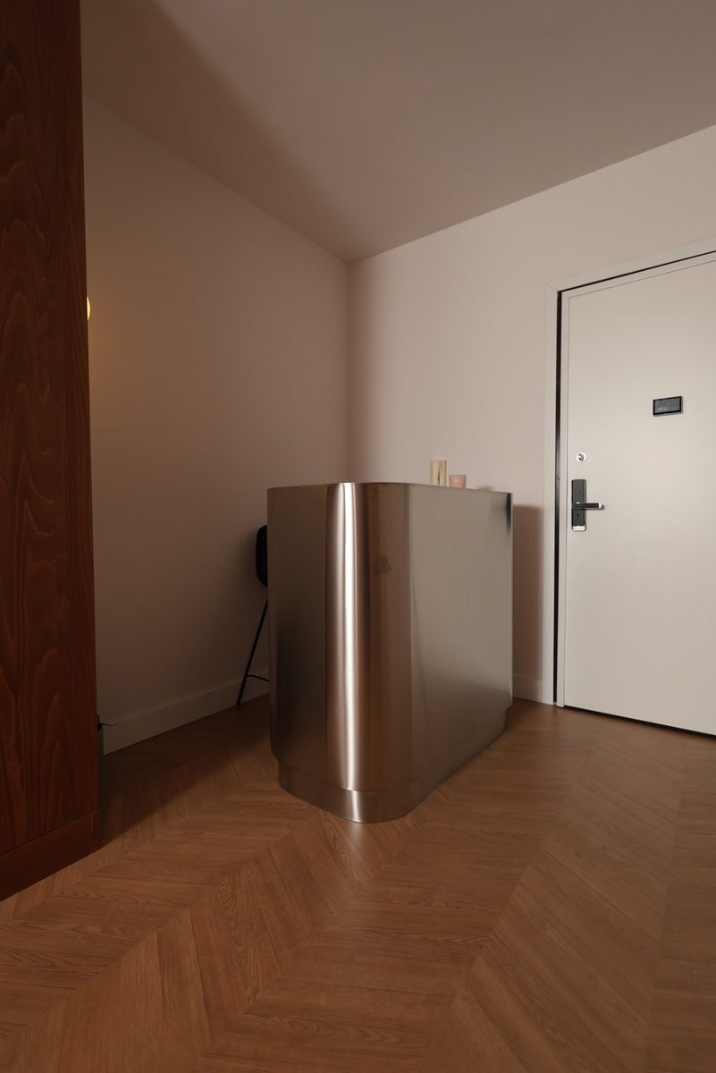 Folded satin stainless steel reception desk curved at the corner of the entrance at La Suite