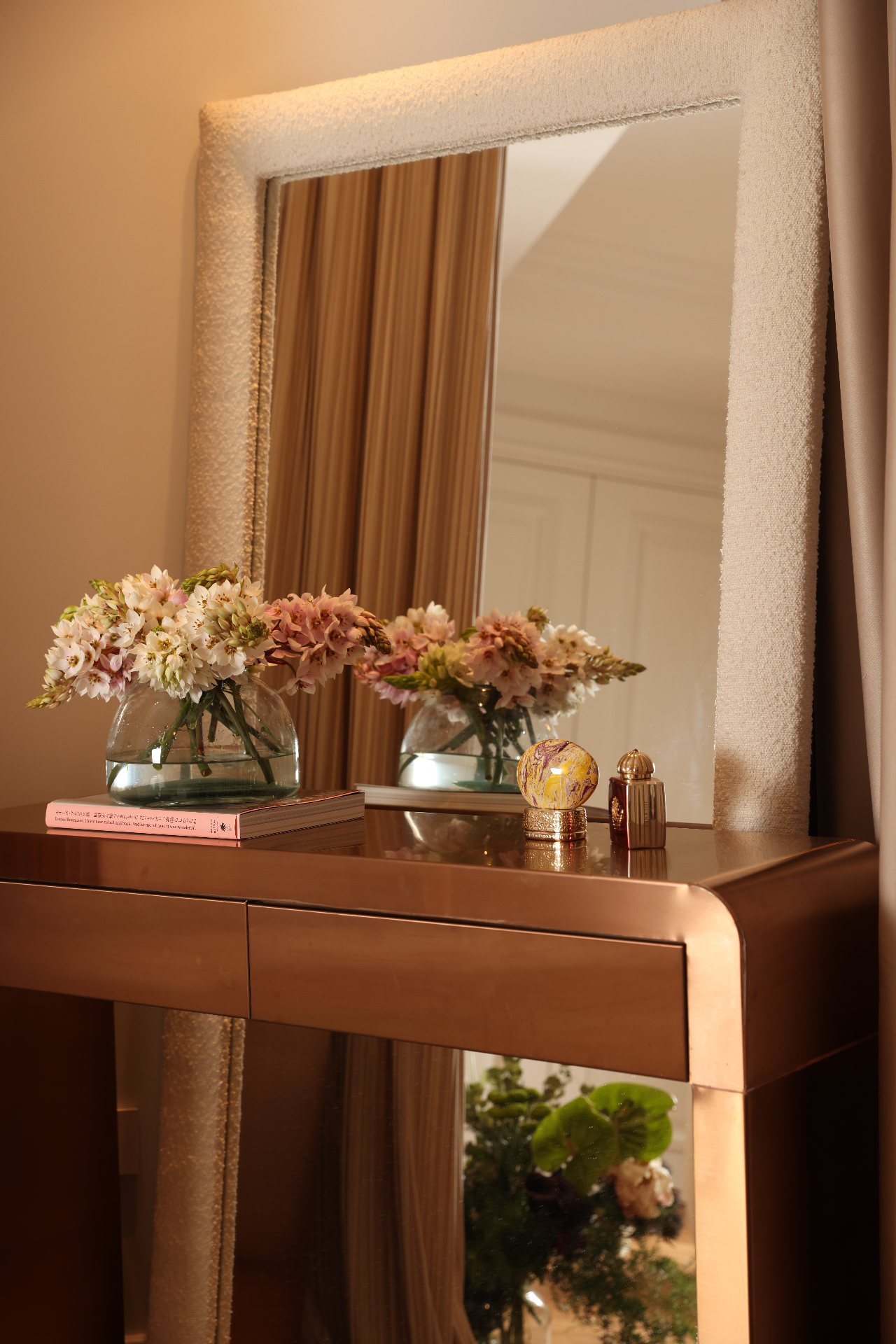 Bronze-toned console with flowers and a reflective backdrop